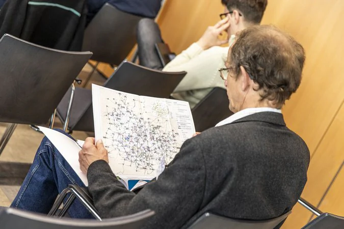 Thüringer Mobilitätskonferenz Eine sitzende Person schaut sich den integralen Taktfahrplan an