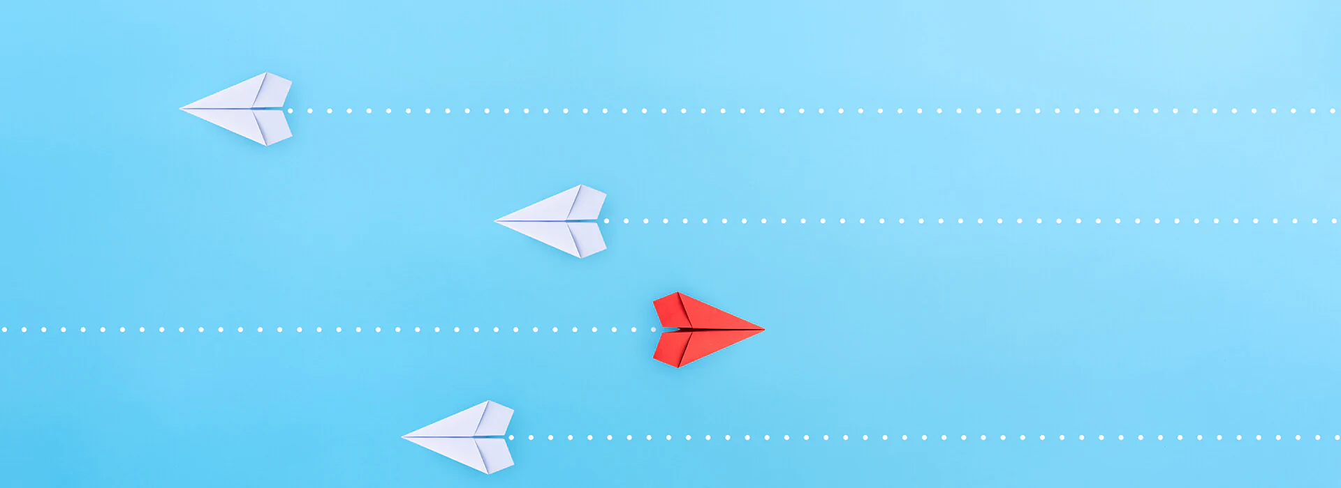 Bildbeschreibung / description: vier Papierflugzeuge von oben, die drei weißen fliegen nach links, der rote nach rechts