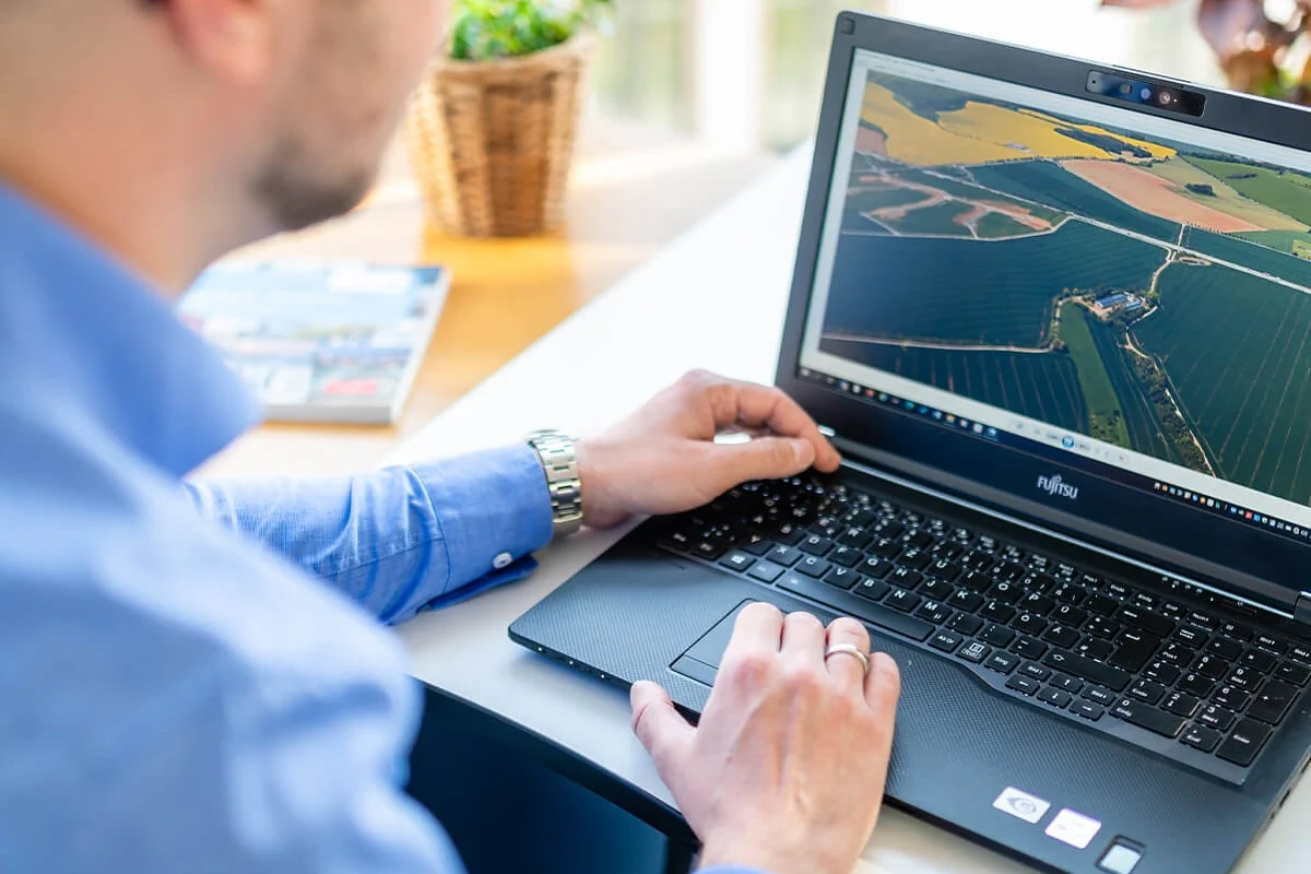 Service Bildbeschreibung / description: Ein Mann arbeitet am Laptop und betrachtet landwirtschaftliche Informationen auf einer Farm.